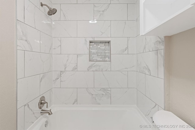 bathroom with toilet and tiled shower / bath