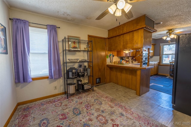 kitchen with kitchen peninsula, a kitchen breakfast bar, ornamental molding, a textured ceiling, and ceiling fan