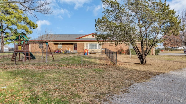 back of property featuring a playground and a yard