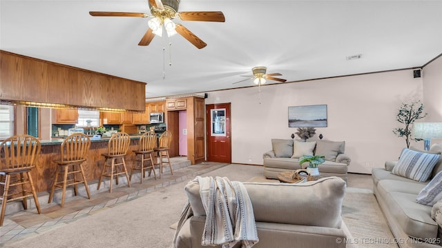 tiled living room with crown molding and ceiling fan