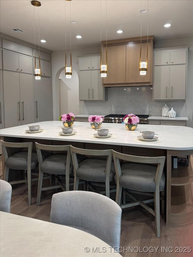 5835 E 139th St S, Bixby, OK 74008 - kitchen featuring wood finished floors, pendant lighting, a kitchen island, a breakfast bar, and recessed lighting