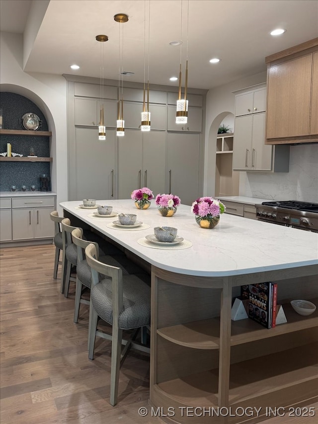 5835 E 139th St S, Bixby, OK 74008 - kitchen featuring open shelves, a breakfast bar, light wood-type flooring, decorative light fixtures, and recessed lighting