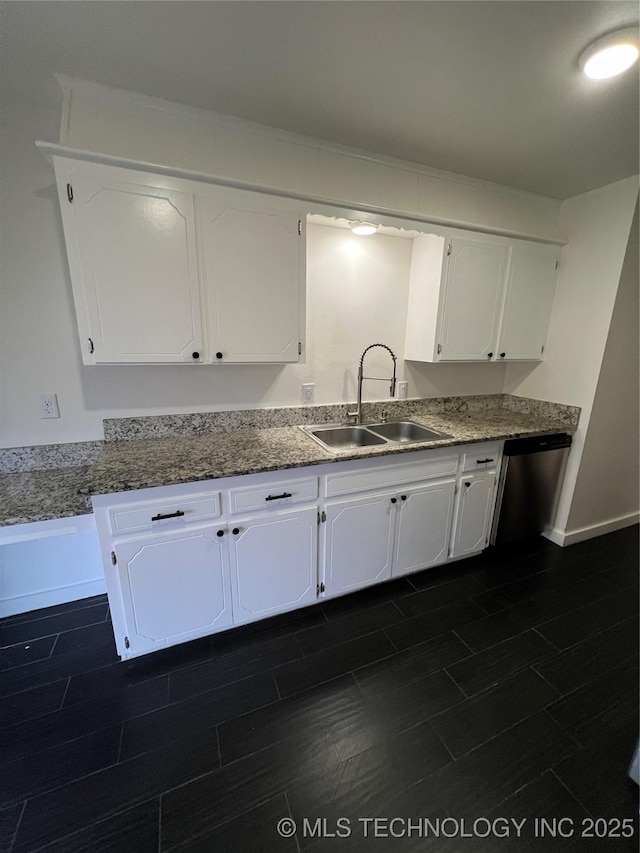 kitchen featuring stainless steel dishwasher, dark stone countertops, white cabinetry, and sink