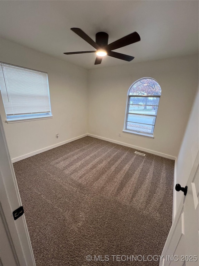 empty room featuring ceiling fan and carpet