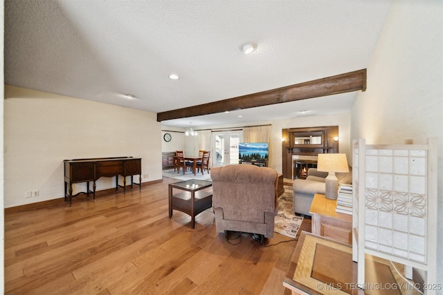 living room featuring a textured ceiling, light hardwood / wood-style floors, and beam ceiling