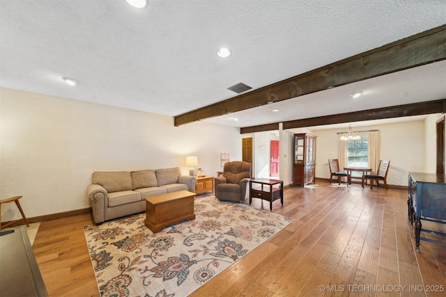 living room with hardwood / wood-style floors, beamed ceiling, a chandelier, and a textured ceiling