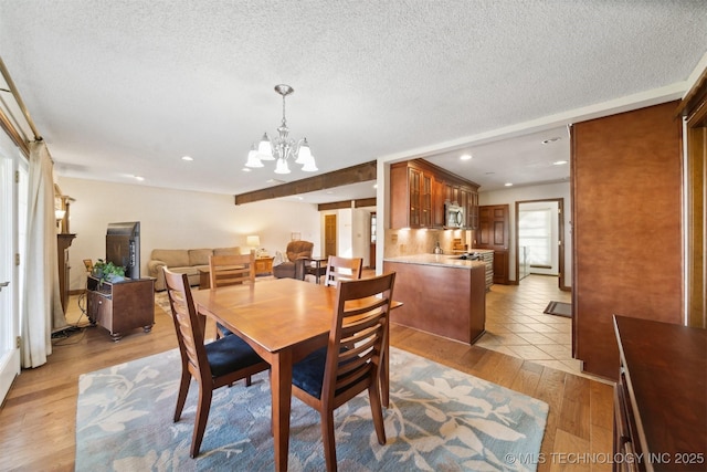 dining area with an inviting chandelier, a textured ceiling, and light hardwood / wood-style flooring