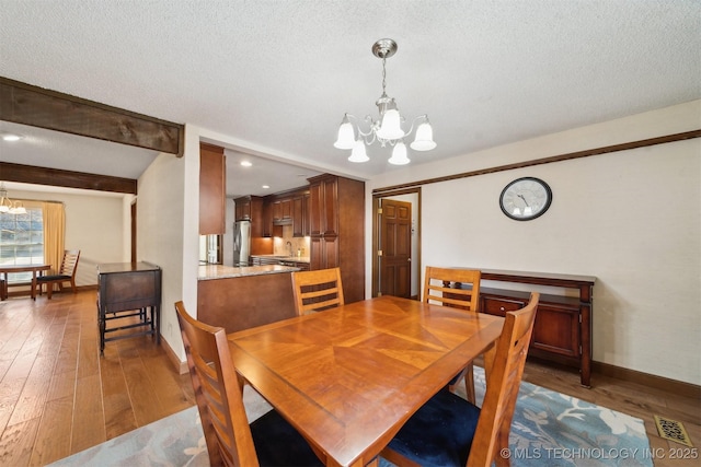 dining space featuring sink, hardwood / wood-style floors, a textured ceiling, and an inviting chandelier