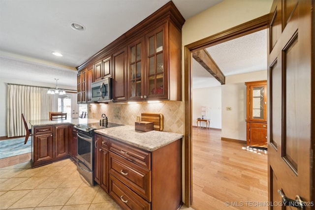 kitchen featuring light stone countertops, beamed ceiling, a notable chandelier, backsplash, and appliances with stainless steel finishes