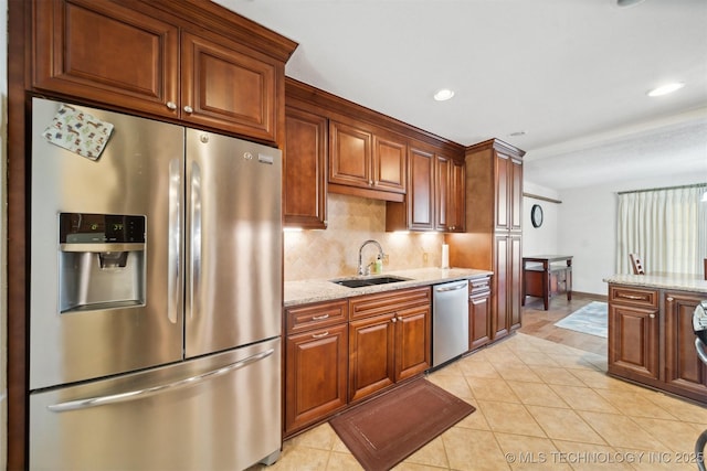 kitchen featuring light stone countertops, sink, backsplash, light tile patterned floors, and appliances with stainless steel finishes