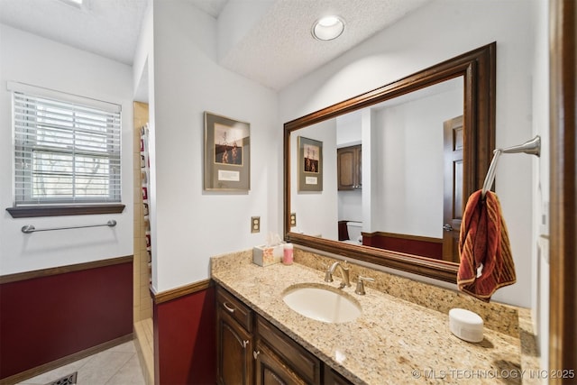 bathroom with tile patterned floors, vanity, and a textured ceiling