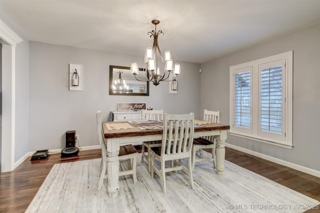 dining area featuring baseboards, an inviting chandelier, and wood finished floors