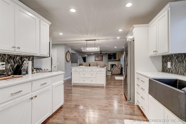 kitchen featuring light wood-style flooring, open floor plan, a fireplace, and white cabinetry