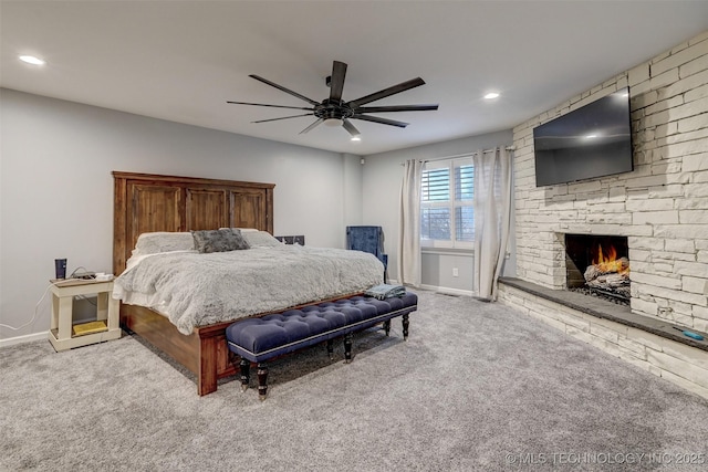 bedroom featuring ceiling fan, a fireplace, and light carpet