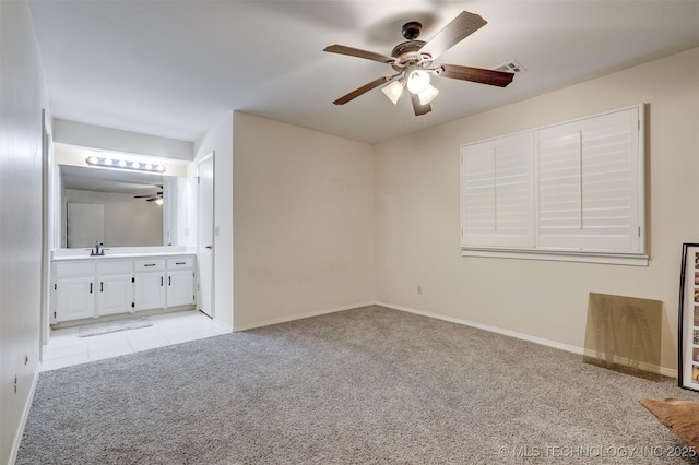 unfurnished bedroom featuring ceiling fan, sink, light carpet, and ensuite bath