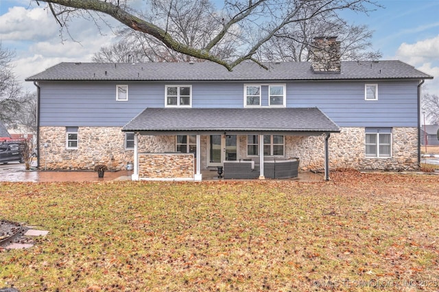 rear view of house with a patio area, stone siding, a lawn, and a chimney