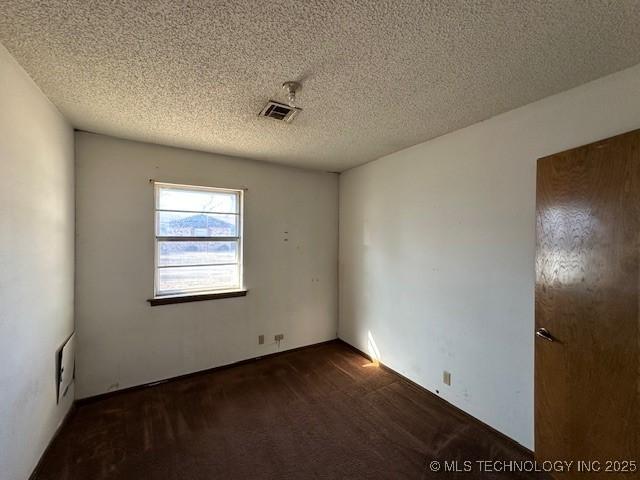 carpeted empty room featuring a textured ceiling