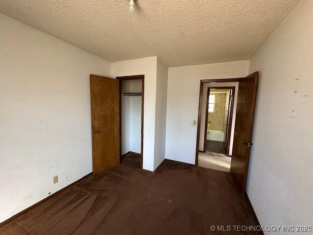 unfurnished bedroom with dark carpet and a textured ceiling