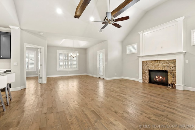 unfurnished living room featuring a fireplace, beamed ceiling, hardwood / wood-style flooring, high vaulted ceiling, and ceiling fan with notable chandelier