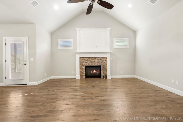 unfurnished living room featuring ceiling fan, wood-type flooring, lofted ceiling, and a stone fireplace