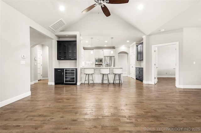 unfurnished living room featuring dark wood-type flooring, lofted ceiling, wine cooler, and ceiling fan