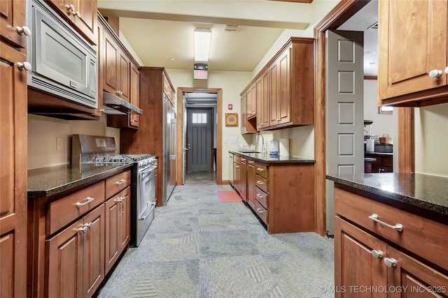 kitchen featuring appliances with stainless steel finishes, sink, and dark stone counters