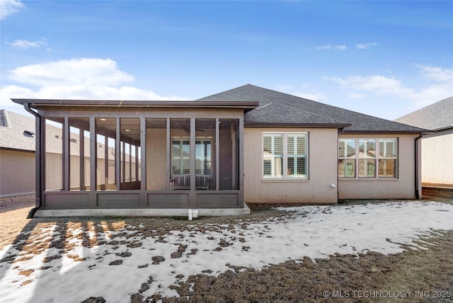 snow covered back of property with a sunroom