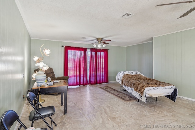 bedroom with a textured ceiling, ceiling fan, and wood walls