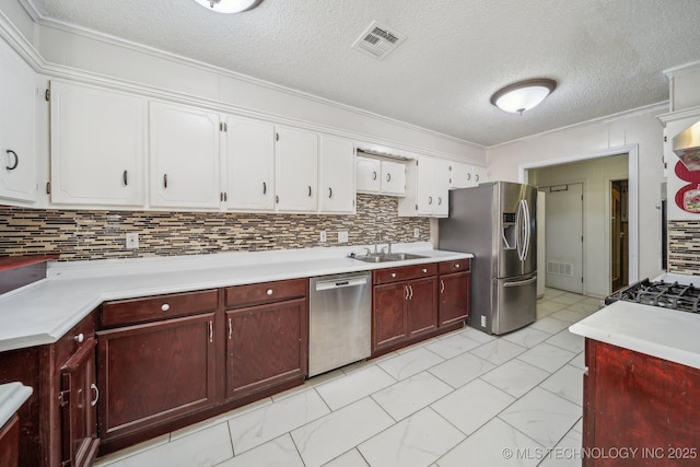 kitchen featuring sink, crown molding, a textured ceiling, decorative backsplash, and appliances with stainless steel finishes