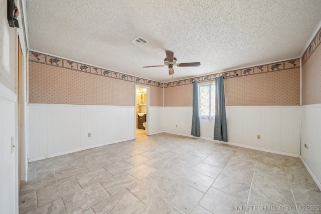 empty room with ceiling fan and a textured ceiling