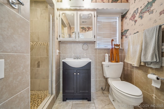 bathroom featuring a tile shower, vanity, toilet, and tile walls