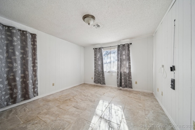 spare room with wooden walls and a textured ceiling