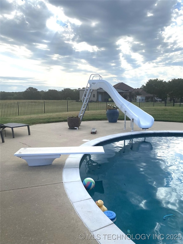 view of pool with a diving board and a water slide