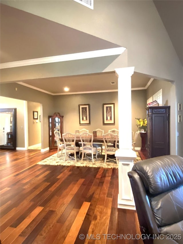 dining area featuring ornate columns, dark wood-type flooring, and crown molding