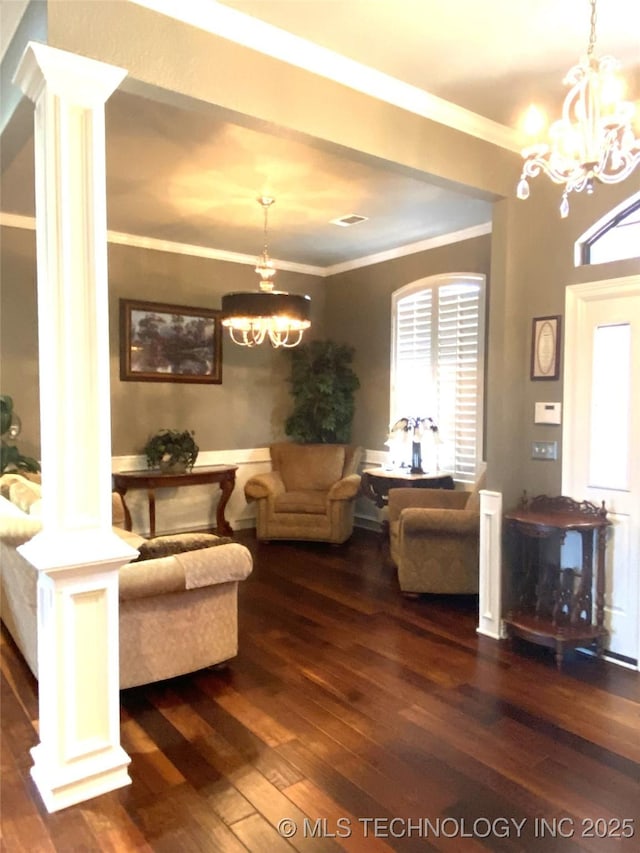 living room with dark hardwood / wood-style flooring, an inviting chandelier, ornate columns, and crown molding