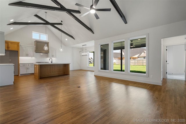 unfurnished living room with dark hardwood / wood-style flooring, plenty of natural light, and beamed ceiling