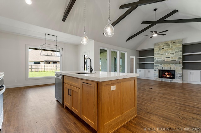 kitchen featuring dishwasher, sink, built in features, a fireplace, and an island with sink