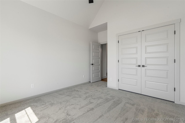 unfurnished bedroom with light carpet, high vaulted ceiling, and a closet