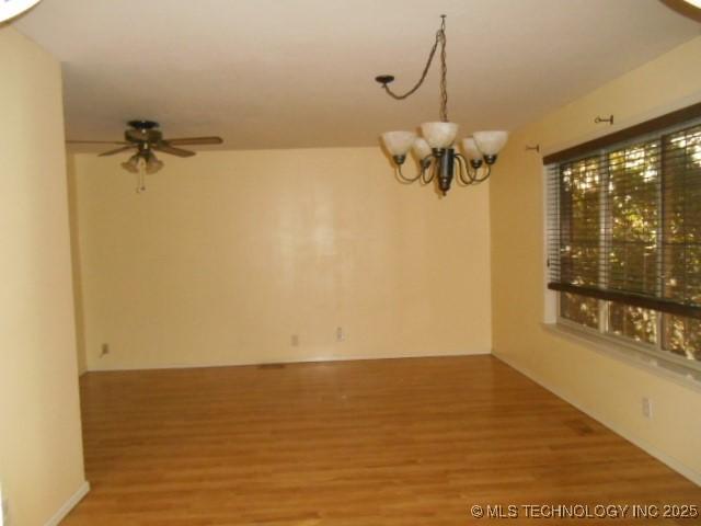 unfurnished room featuring hardwood / wood-style floors and ceiling fan with notable chandelier