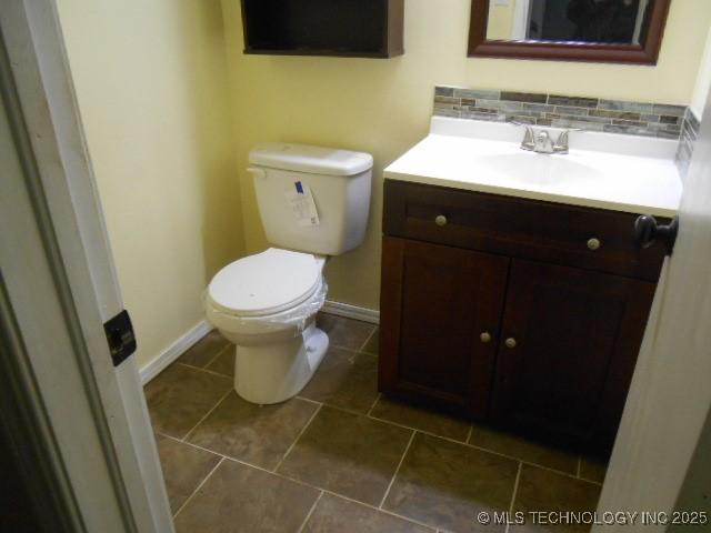 bathroom with decorative backsplash, vanity, and toilet