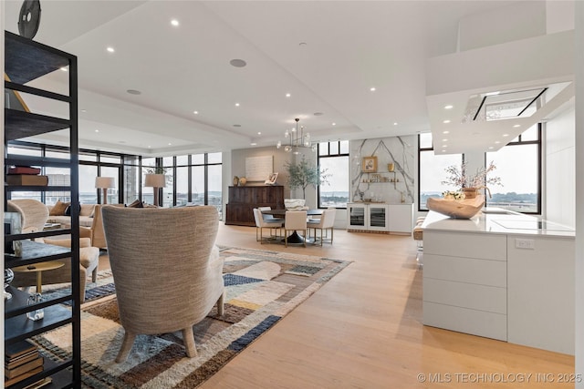 living room with floor to ceiling windows, light wood-type flooring, beverage cooler, and an inviting chandelier