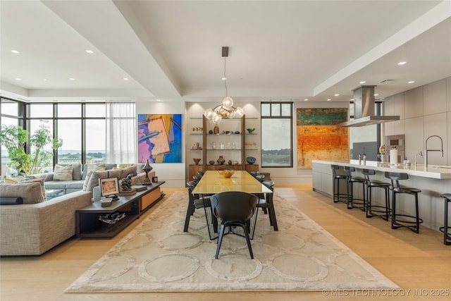 dining area featuring light hardwood / wood-style floors, sink, and an inviting chandelier