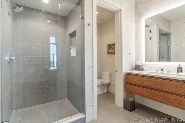 bathroom with tile patterned floors, a shower with door, vanity, and toilet