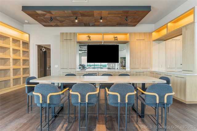 kitchen featuring dark hardwood / wood-style floors, light brown cabinetry, beam ceiling, a kitchen bar, and wood ceiling