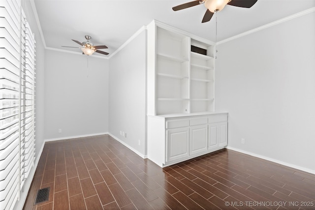 empty room featuring built in features, ceiling fan, and crown molding