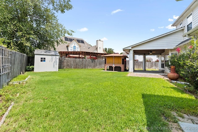 view of yard with ceiling fan, a shed, and a patio