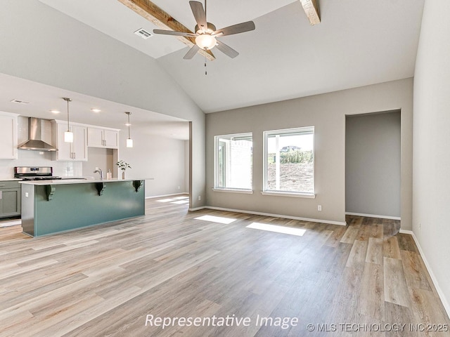 unfurnished living room featuring ceiling fan, sink, lofted ceiling, and light wood-type flooring