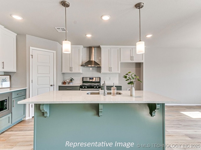 kitchen featuring pendant lighting, wall chimney exhaust hood, and white cabinets