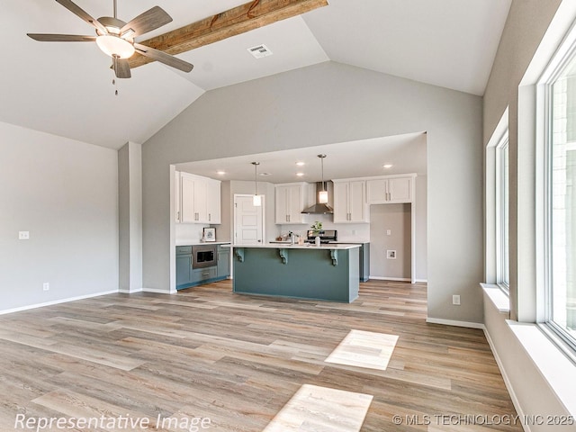 kitchen featuring white cabinets, decorative light fixtures, a kitchen island, and wall chimney range hood