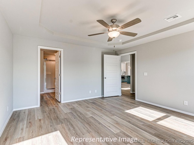 empty room featuring ceiling fan, a raised ceiling, and light hardwood / wood-style flooring